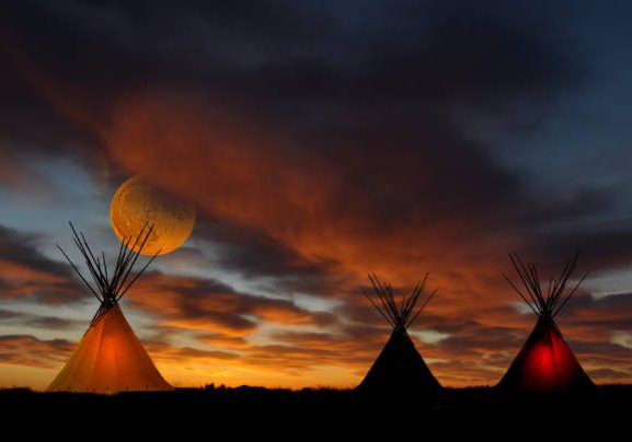 A prairie First Nation teepee cam at sunset. Full moon